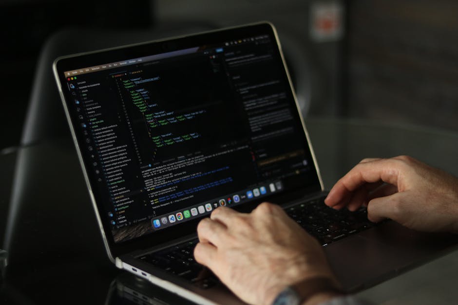 A close-up view of a laptop displaying lines of code on its screen, with a ceramic coffee mug positioned slightly behind it. The mug has a beige background with black and dark red text that reads 'Thi